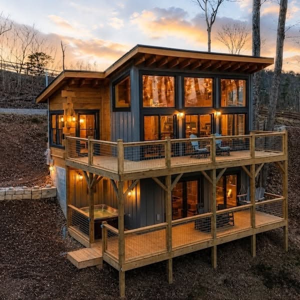 Modern Two-Story Cabin with Expansive Decks and Large Windows at Sunset